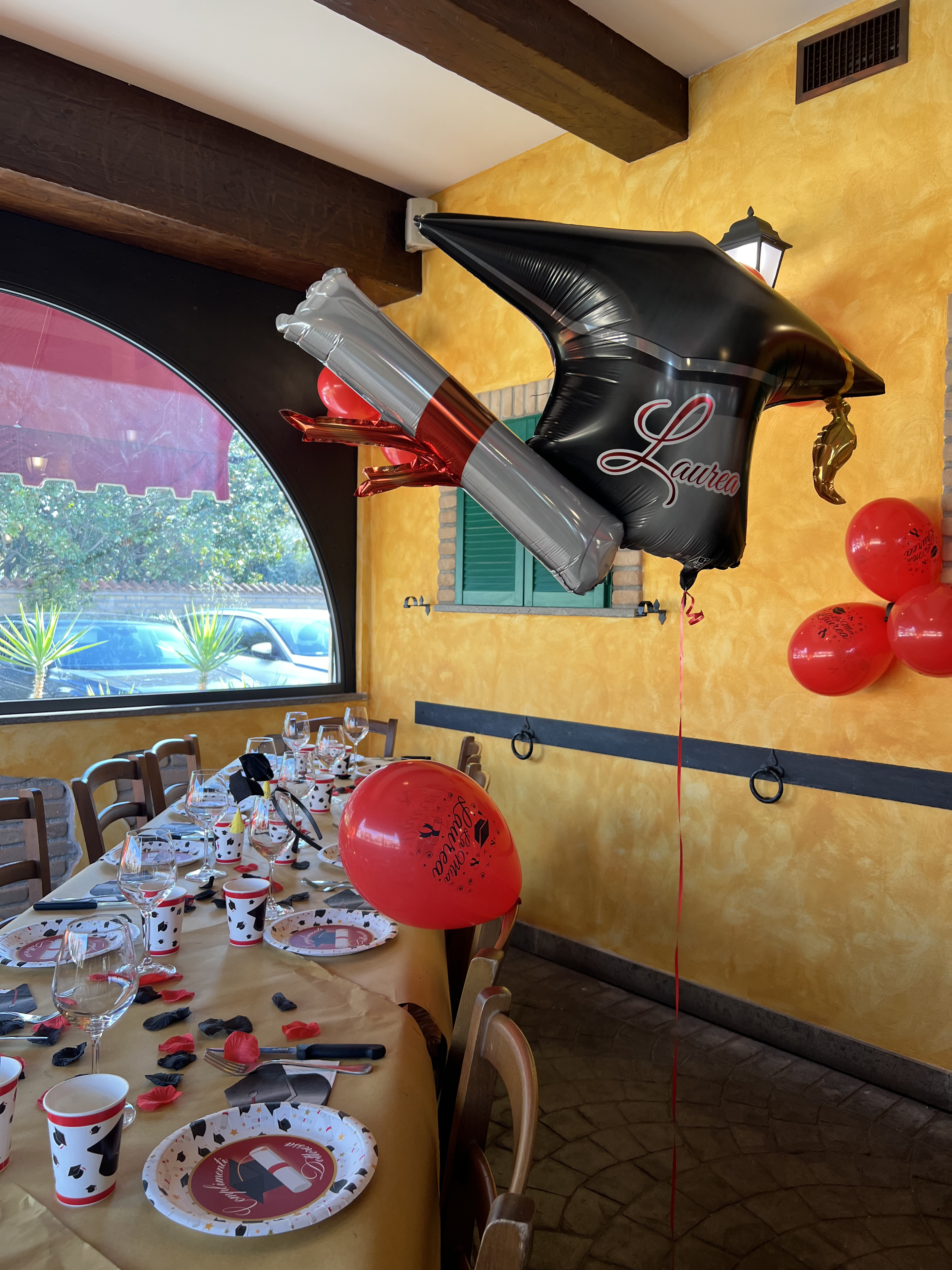 Tavolata allestita in rosso e nero con palloncino Laurea